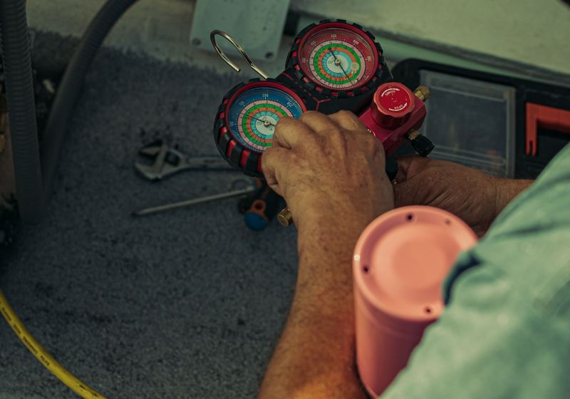 HVAC technician reading refrigerant manifold gauges during a system check